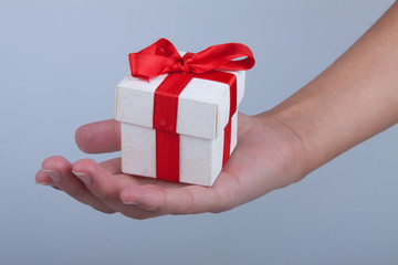 Женская рука протягивает коробку с подарком