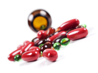 Colorful pills spread in front of a pill bottle.