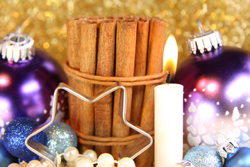 Kerze mit Zimtstangen und lila Baumkugeln