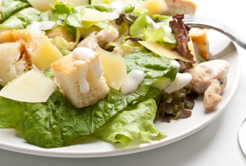 traditional caesar salad on white plate with a fork