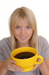 Junge  Frau  trinkt Kaffee aus einer gelben Tasse