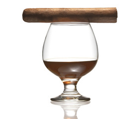 Glass of cognac with cigar on top