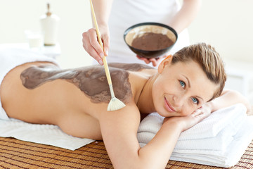 Delighted caucasian woman receiving a beauty treatment with mud