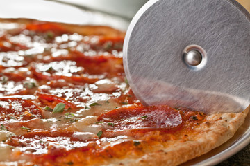 Pepperoni Pizza being cut with pizza cutter