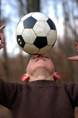 Junge balanciert Ball auf der nase