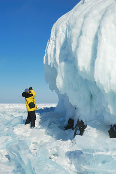 Photographer getting picture of ice cornice on the rock.