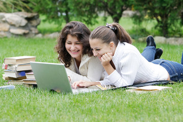 two student girls with laptop on natural background