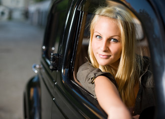 Obraz na płótnie Canvas Beautiful young boonde posing with black vintage car.