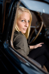 Fototapeta na wymiar Beautiful young boonde posing with black vintage car.