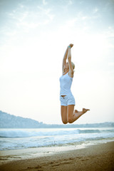 Happy young woman is jumping on the beach