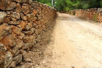 masonry stone wall fence around sand soil track