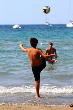 Boys playing soccer on the seashore