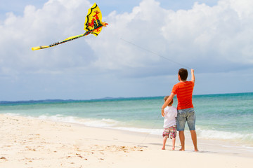 Father and son flying kite on beach