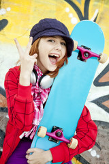 Closeup portrait of a happy young girl with skateboard and graff