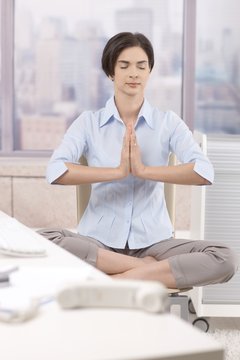 Female office worker meditating at work