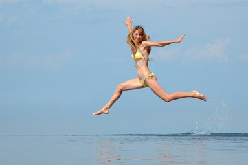 Naklejka premium The woman in a bathing suit jumps on water