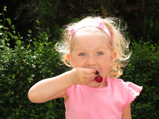 Little girl eats cherry