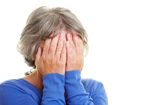 Seniorin h&auml;lt sich H&auml;nde vor Gesicht