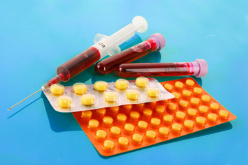 Medical test tubes with blood and medicines on blue