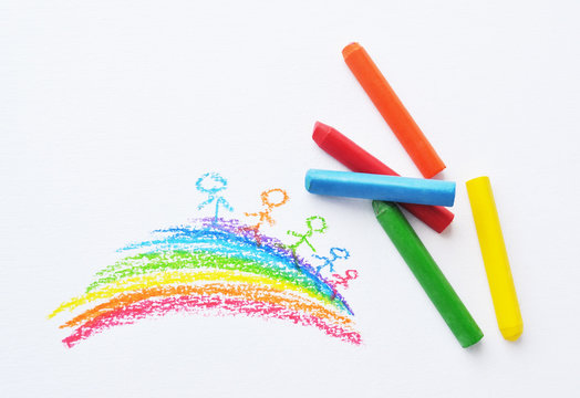Colorful crayons and kid's drawing with rainbow