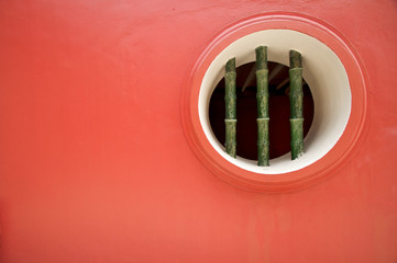 Solid red wall with bamboo window feature
