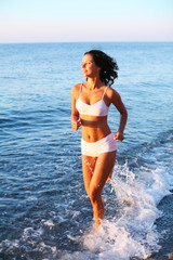 Sexy brunette is running on the beach