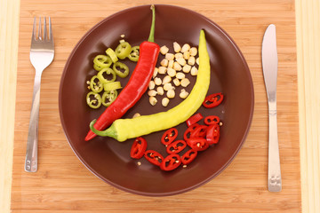 Plate with pepper, fork and knife on the wooden table