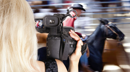 Blonde woman video recording horce race - 25823519