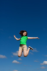 Fototapeta na wymiar Girl jumping, running against blue sky