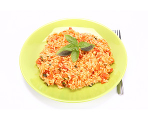 Risotto with tomatoes on a green plate decorated with basil