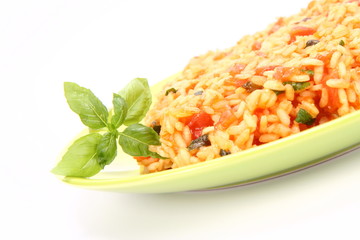 Risotto with tomatoes on a green plate decorated with basil