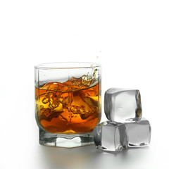 Glass with splashing whisky drink on a white background