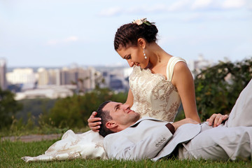 Happy wedding couple lying on the grass in the park