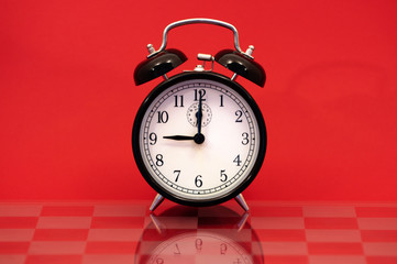 Vintage Alarm Clock Showing 9 O'Clock Isolated on Red Background