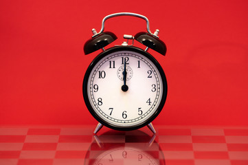 Alarm Clock Showing 12 O'Clock Isolated on Red Background
