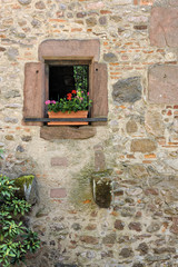 Fototapeta na wymiar Little window decorated with flowers in windowbox in a medieval