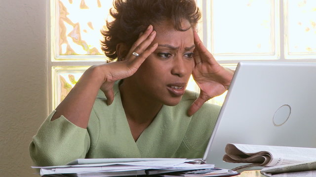 Portrait of concerned woman with laptop and bills