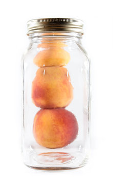 Canning peaches beside a glass jar on isolated background