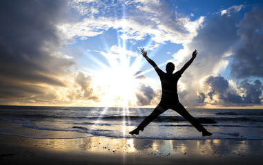 happy man jumping on the beach with beautiful sunrise