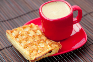 cup of cappuccino and waffles on a bamboo mat