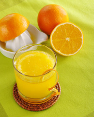 Fresh orange juice and squeezer on green (Selective Focus)