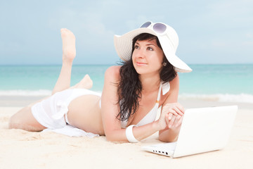 Cute woman with white laptop on the summer beach