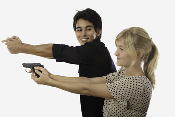 asian man teaches a young woman how to aim a pistol