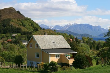 Fototapeta na wymiar Alleinstehendes Holzhaus vor einer sommerlichen Landschaft