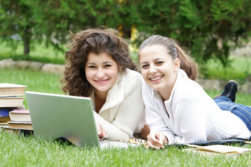 two smiling girls with laptop on natural background