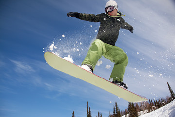 Snowboarder jumping through air with  blue sky in background