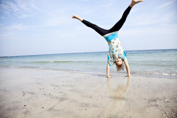 Young girl show an acrobatic on the beach.