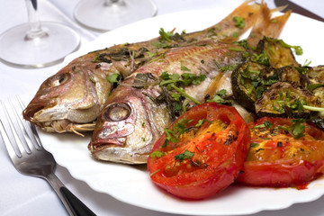 Two Grilled fish with vegetables and herbs on the dish