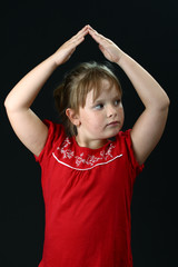 Small girl making roof from hands above her on black