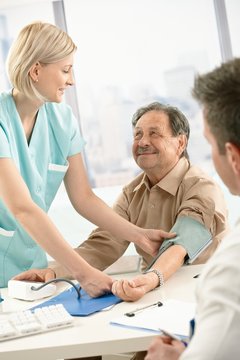 Smiling nurse measuring blood pressure of patient